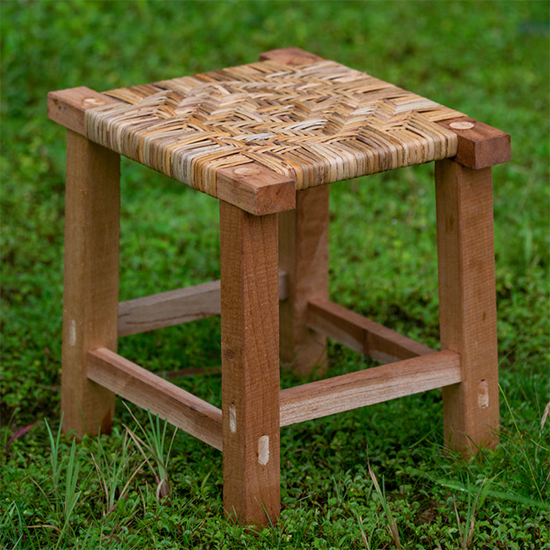 Small hand-braided rattan stool on a wooden frame – shown outdoors