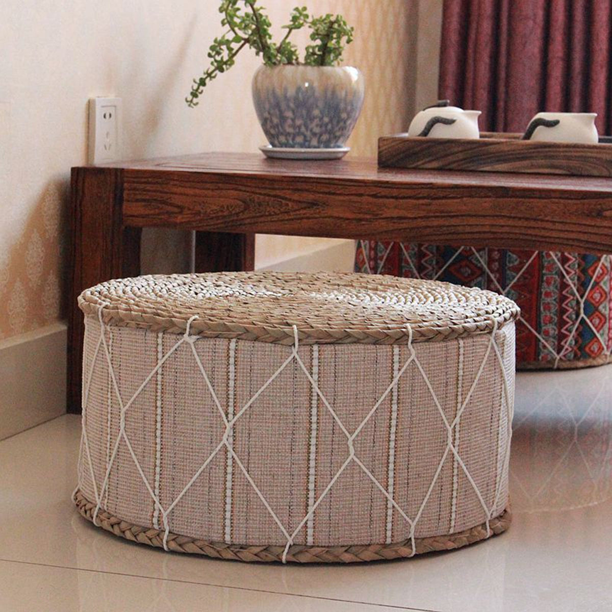 Round beige pouf with a hand-braided rattan frame – shown in a room setting