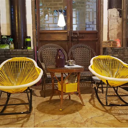 Modern yellow lacquered rattan rocking chair – shown in a room setting