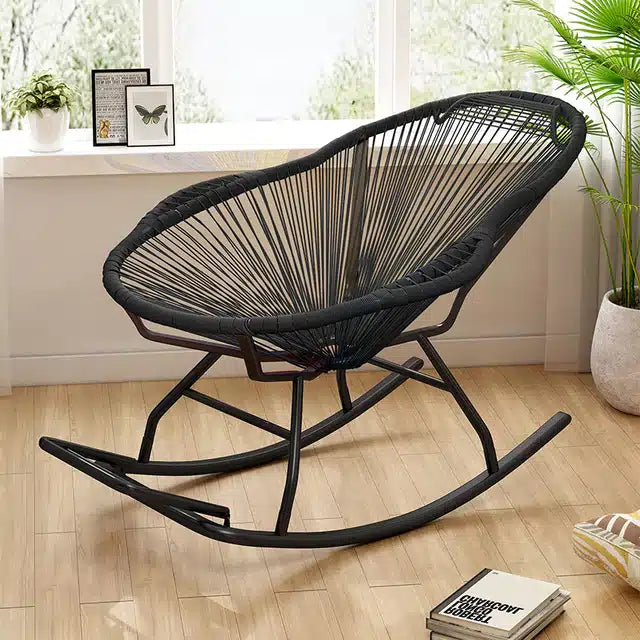 Modern black rattan rocking chair with a hand-braided seat – shown in a room setting