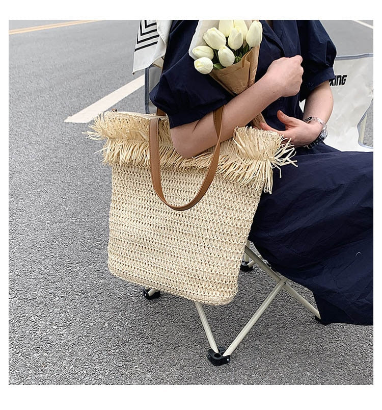 Large white straw crossbody bag with fringe trim – worn by a model