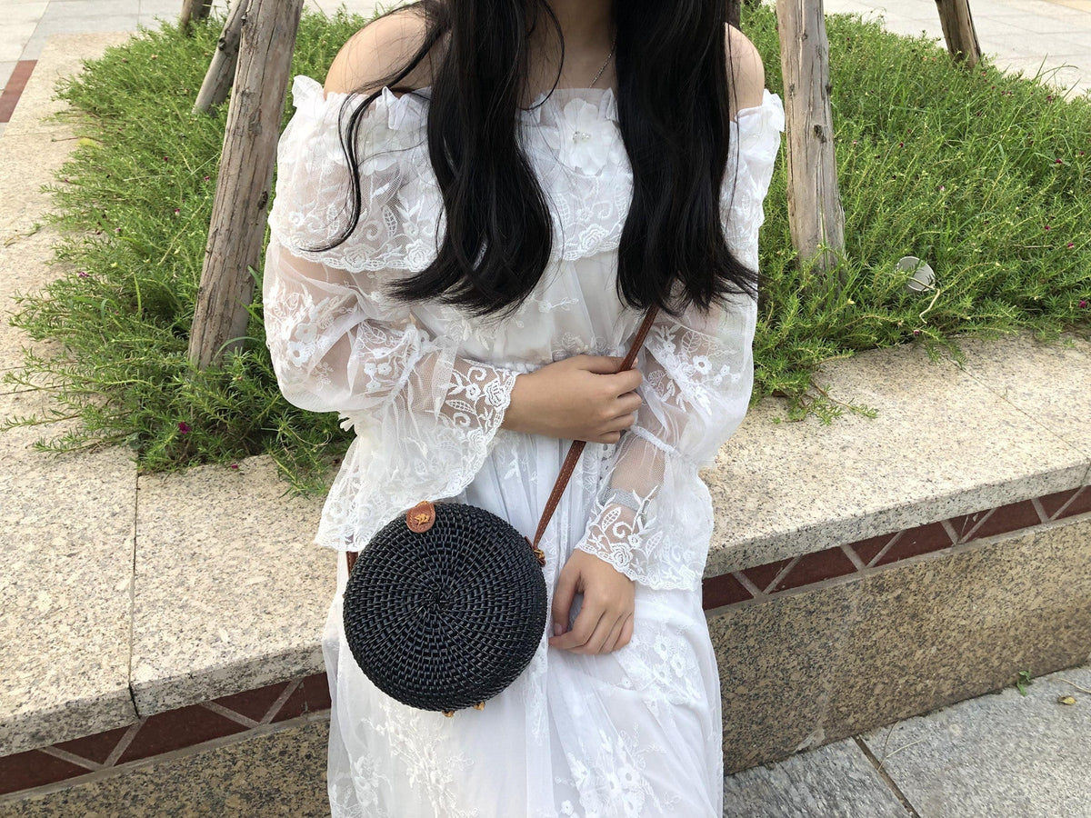 Round boho handwoven rattan handbag – black version, worn by a model