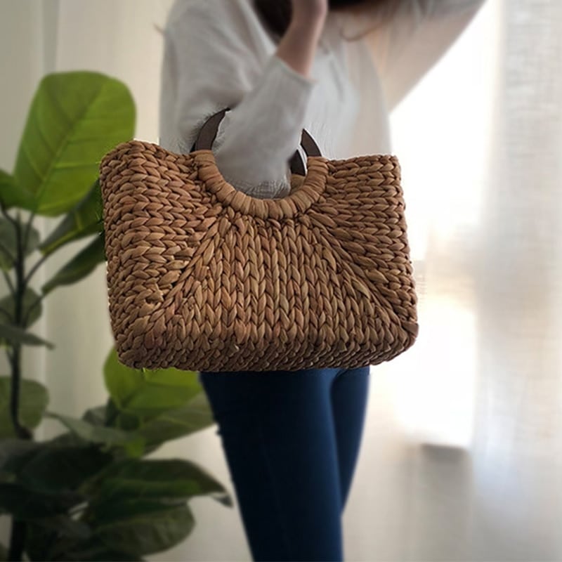Handmade rattan beach bag with outer pockets – worn by a model
