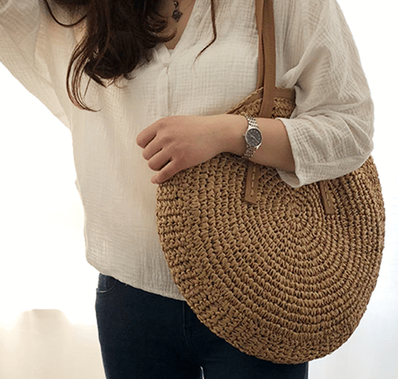 Caramel brown woven rattan beach bag – worn by a model