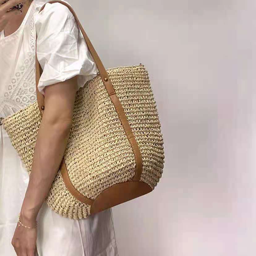 Handwoven straw handbag – beige variant, worn by a model
