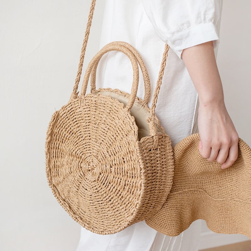 Round rattan handbag with a tight braid – brown variant, worn by a model