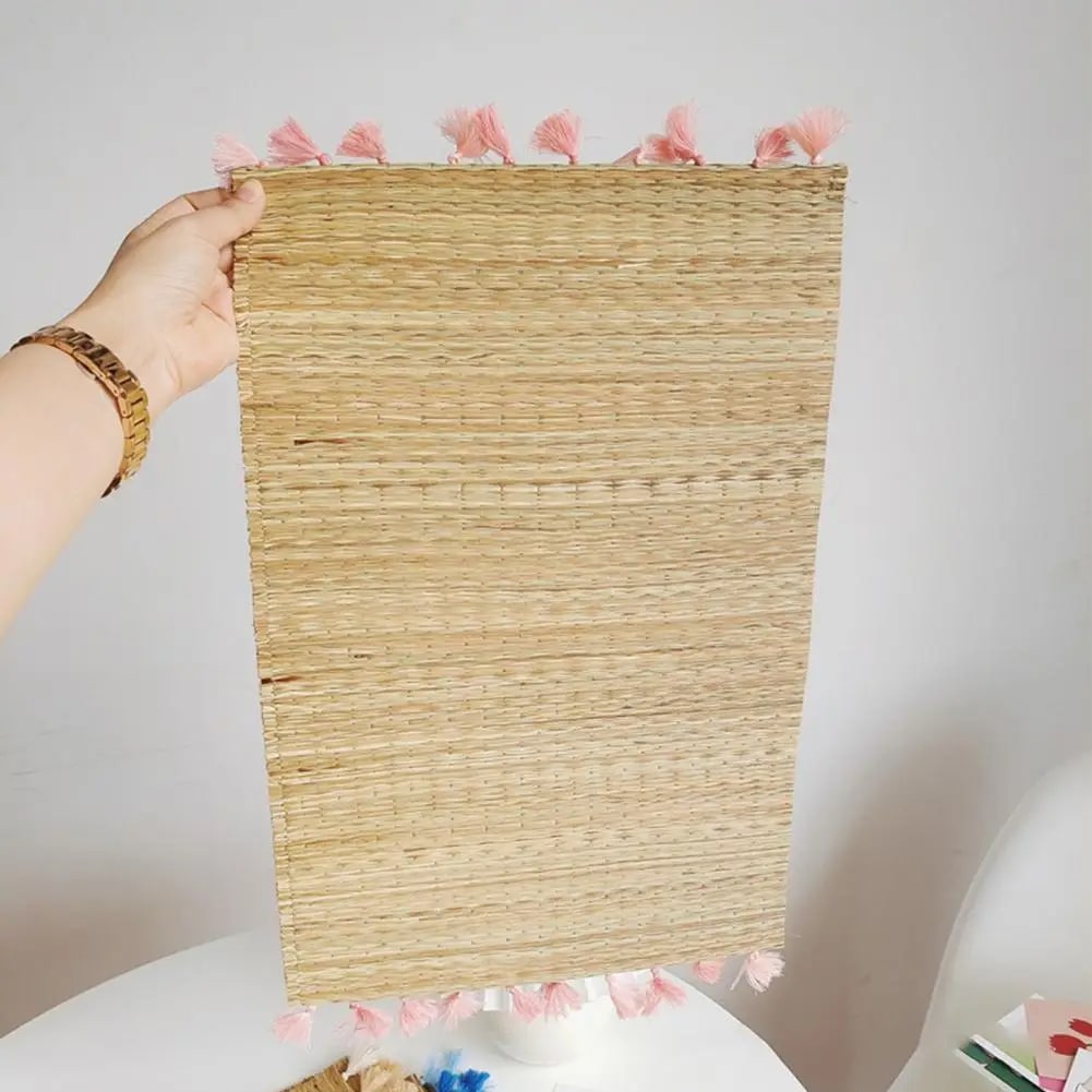 Rectangular straw placemat with pink tassels at the corners – shown in use
