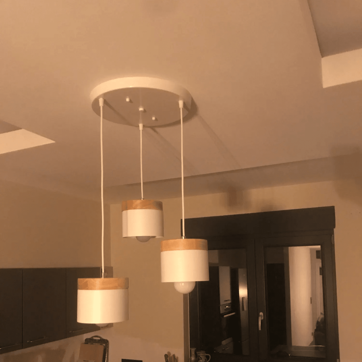 Modern LED wood slat and brushed aluminum ring pendant – shown lit in a room setting