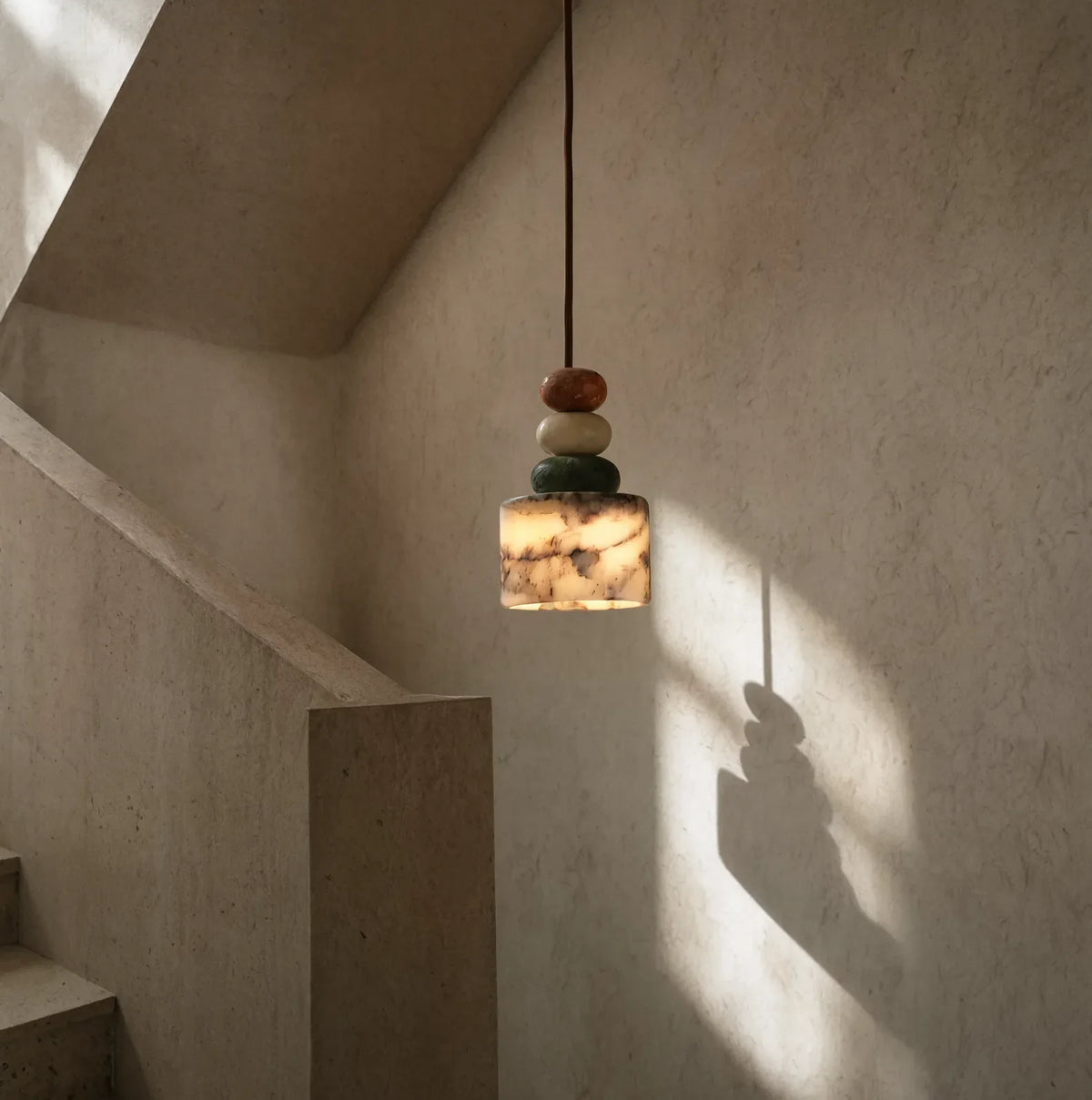 Agrigente stacked stone and marble pendant light – shown lit in a stairwell