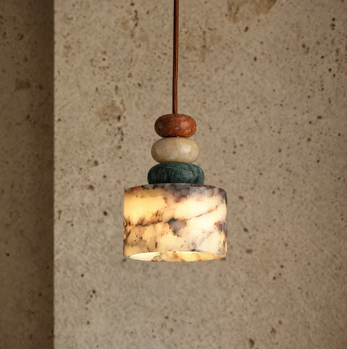 Agrigente stacked stone and marble pendant light – shown lit in a room setting (3)