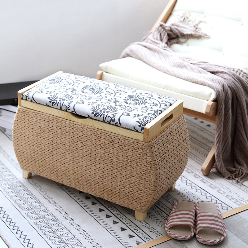 Light rattan storage stool with black embroidered florals on the lid – shown in a room setting