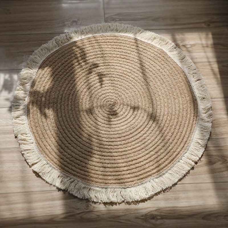 Round handmade cotton and linen rug with a pom-pom fringe – shown in a room setting