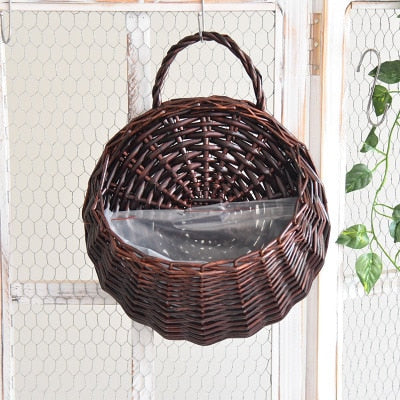Round hanging rattan wall vase with golden highlights – brown variant, shown in a room setting