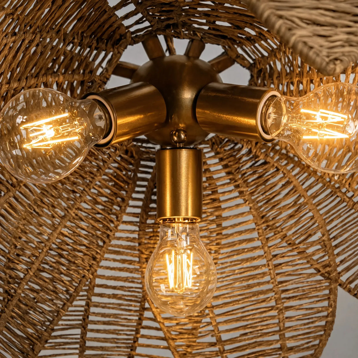 Detail of a rattan flower pendant light with a brass center and lit bulbs