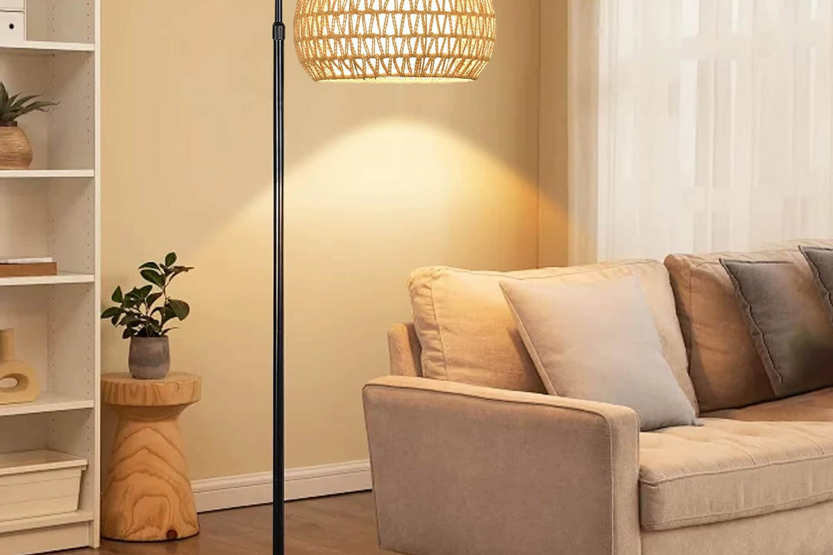 Bohemian rattan floor lamp with a hand-braided shade – shown lit in a room setting
