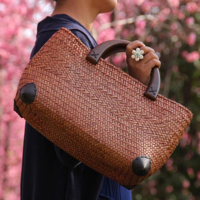 Elegant rattan tote with polished wooden handles – shown in a room setting