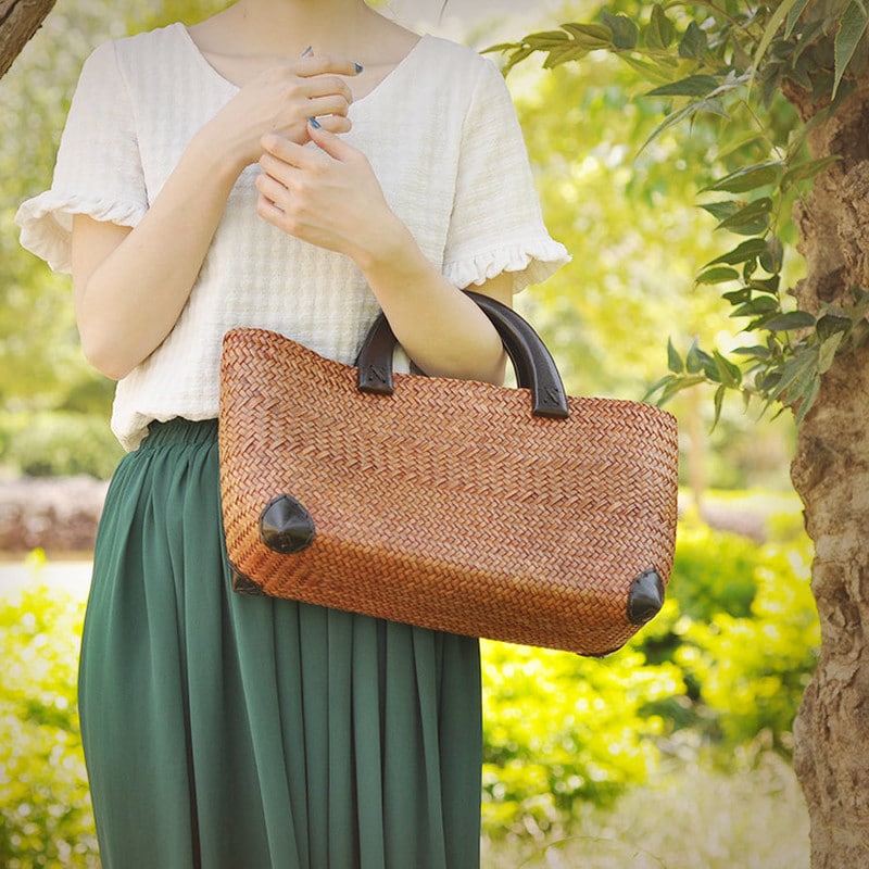 Elegant rattan tote with polished wooden handles – worn by a model (2)
