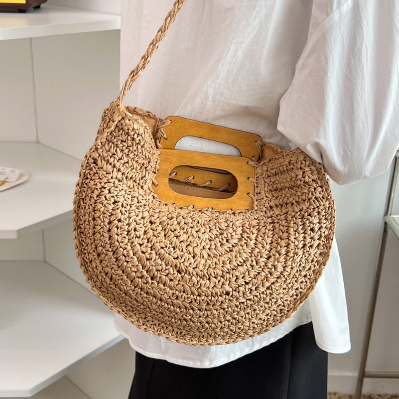 Rounded rattan handbag with a raw wood handle