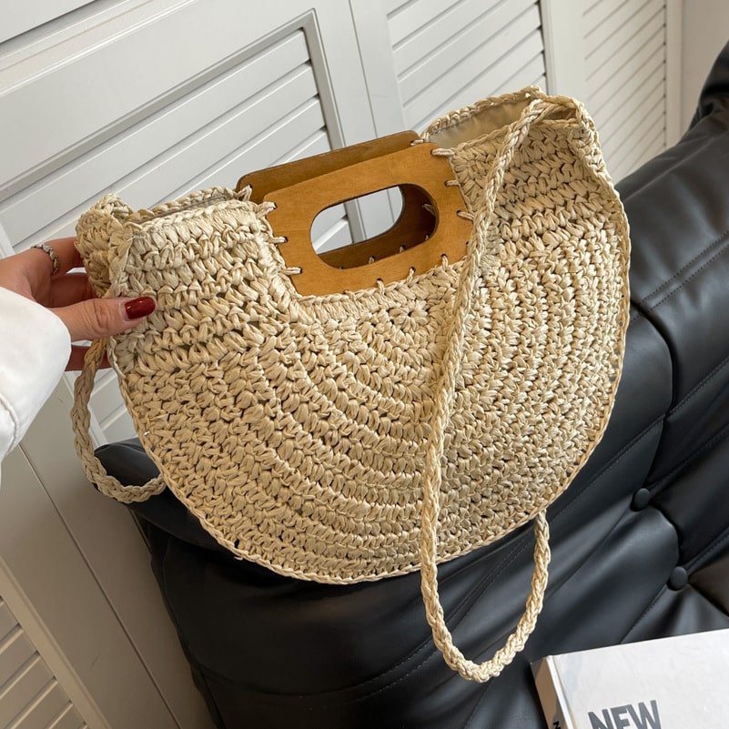Rounded rattan handbag with a raw wood handle – worn by a model (2)