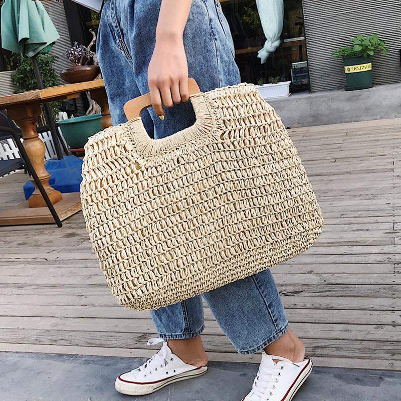 Woven straw tote with varnished wooden handles – worn by a model (2)