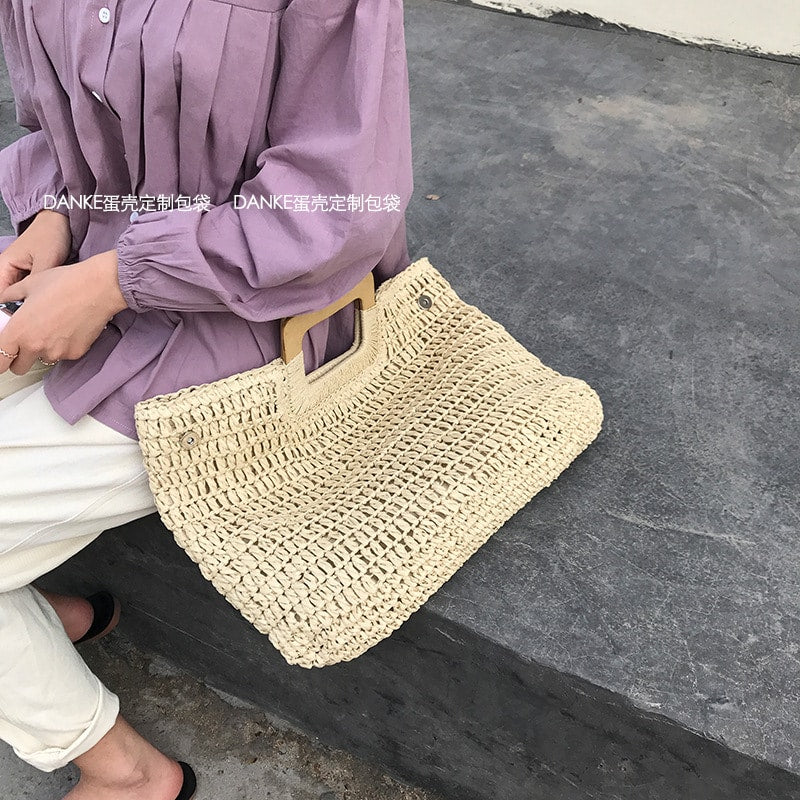 Woven straw tote with varnished wooden handles – worn by a model (3)