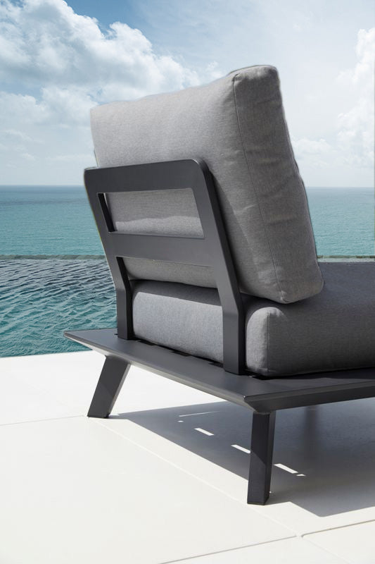 Armless chair from the Tiny black modular aluminum outdoor sofa with chaise and square coffee table – shown outdoors