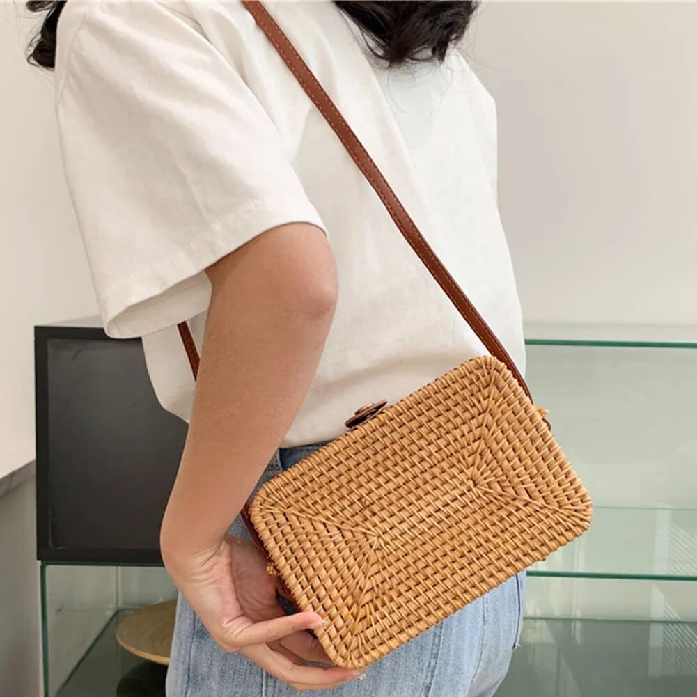 Rectangular rattan handbag with a button closure – worn by a model