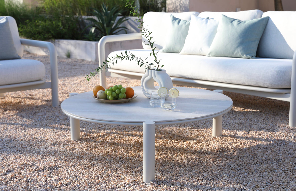 Coffee table from the Amaia aluminum and rope patio set with cylindrical sofa and ceramic table – shown outdoors