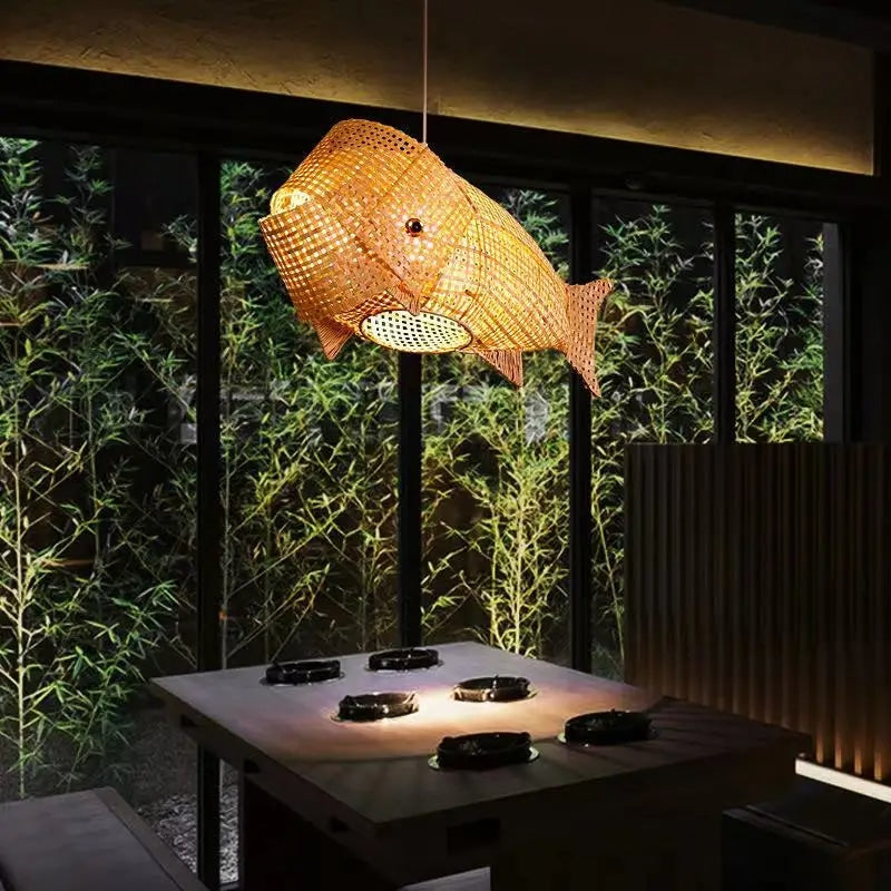 Handwoven rattan koi carp shaped ceiling light – shown lit in a room setting
