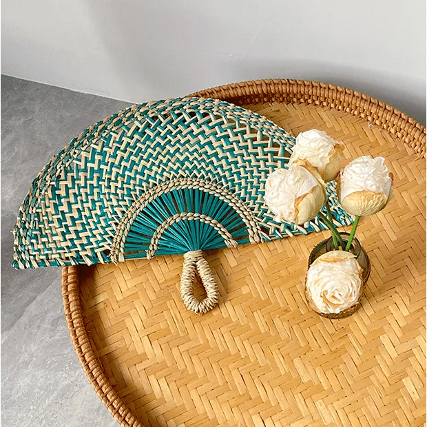 Green woven rattan fan wall decor with radiating ribs – shown in a room setting