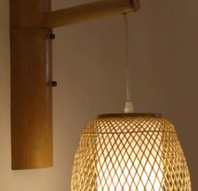 Handwoven round rattan wall sconce with a cascade of fringe – shown lit (2)