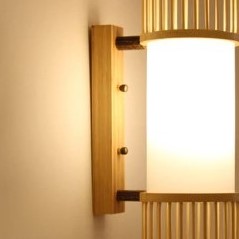 Handwoven cylindrical rattan wall sconce – close-up detail, lit