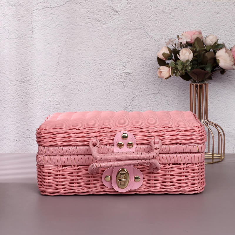 Handwoven rattan makeup organizer with integrated handles – pink variant, shown in a room setting