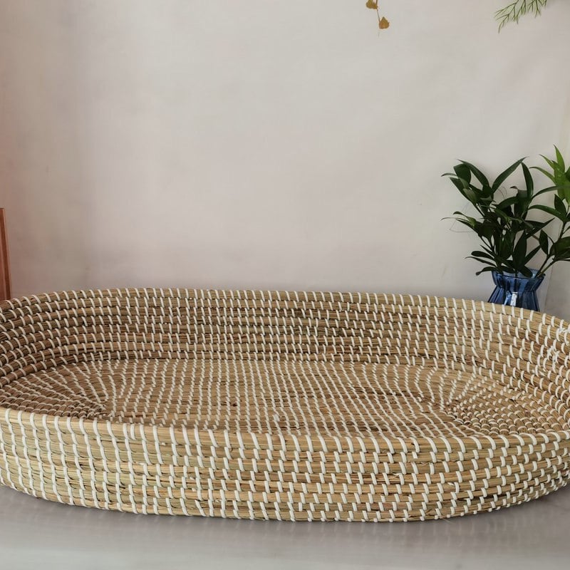Braided rattan moses basket with integrated handles – shown in a room setting