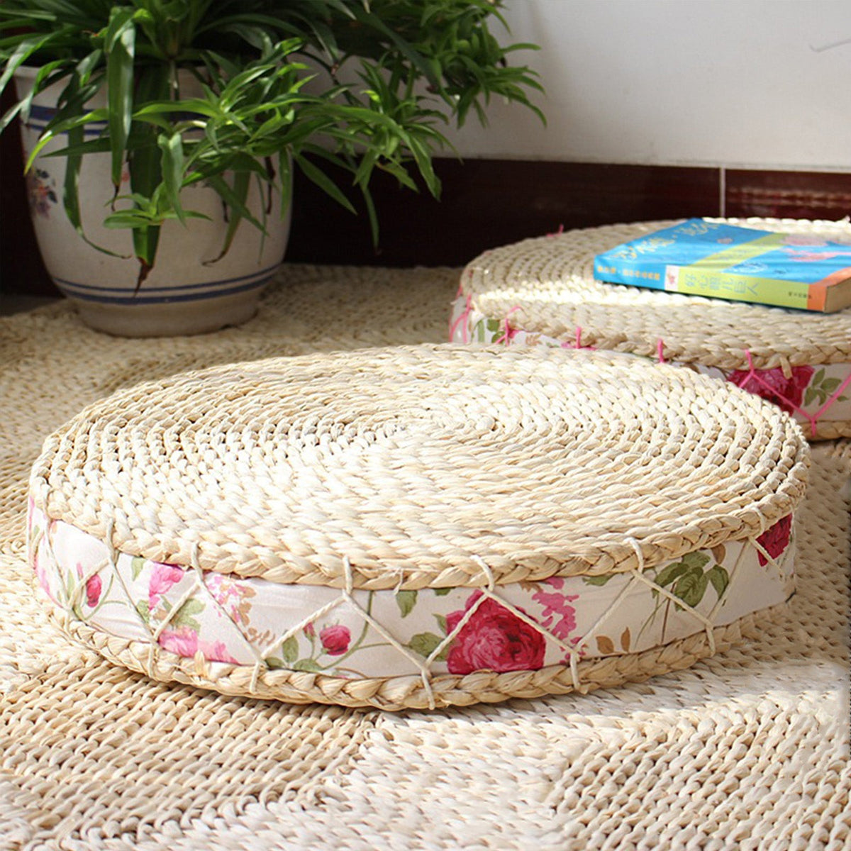 Round rattan-framed cushion with a white rose-print border – shown in a room setting