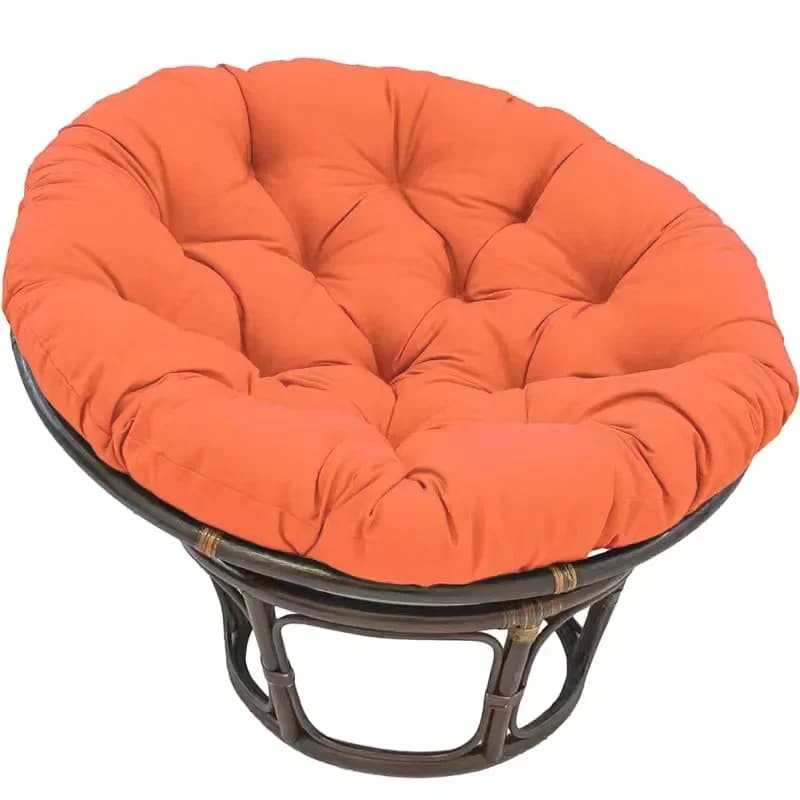 Thick pouf-style plush cushion for a rattan loveseat – orange variant, shown in a room setting