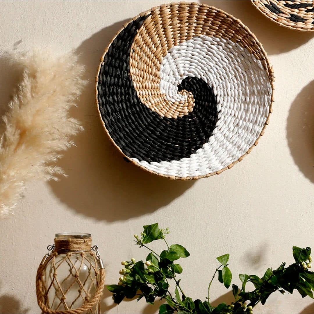 Round rattan wall hanging trimmed with ecru cotton pom-poms – shown in a room setting (2)