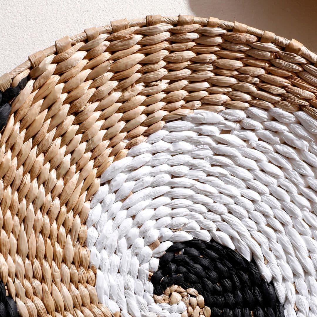 Round rattan wall hanging trimmed with ecru cotton pom-poms – close-up detail