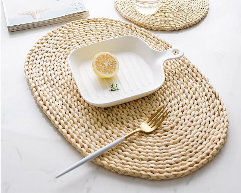 Oval woven rattan trivet – shown in a room setting
