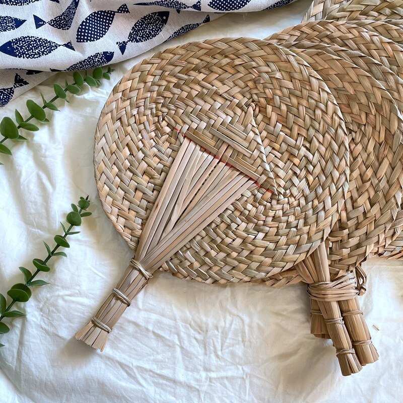 Round hand-woven rattan hand fan – shown in a room setting