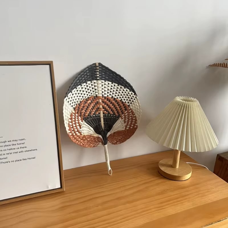 Braided raw rattan fan mounted on a slim stick – shown in a room setting