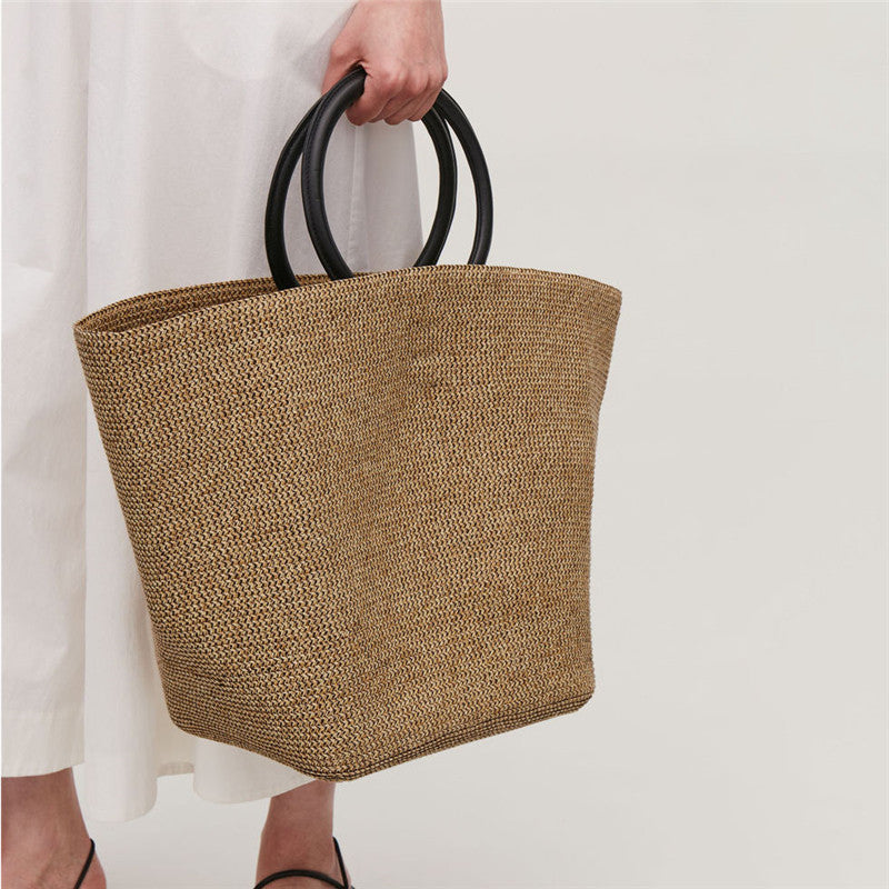 Large oval rattan handbag with a leather handle and bamboo clasp – worn by a model