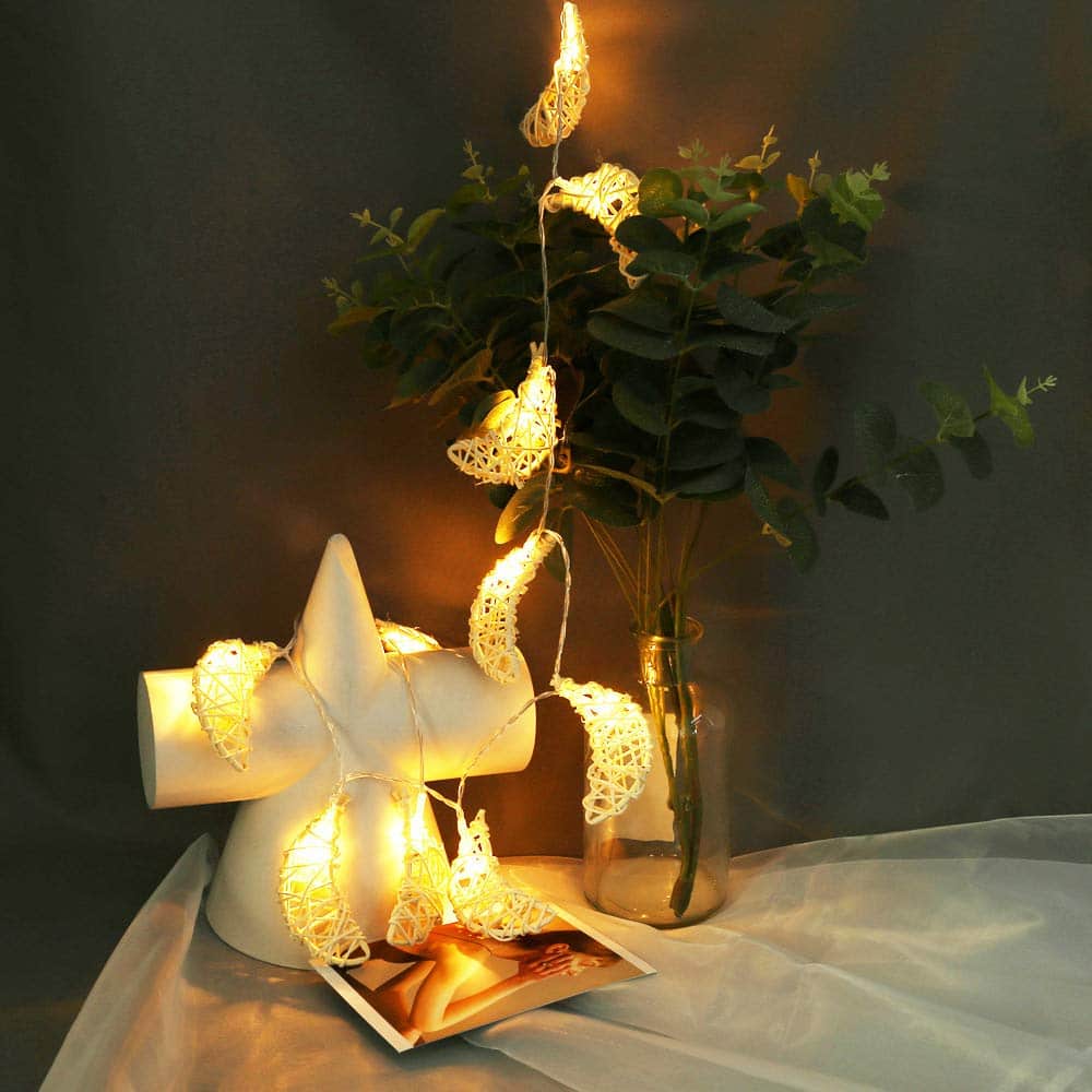 Handwoven rattan crescent moon light with warm white LEDs – shown lit in a room setting