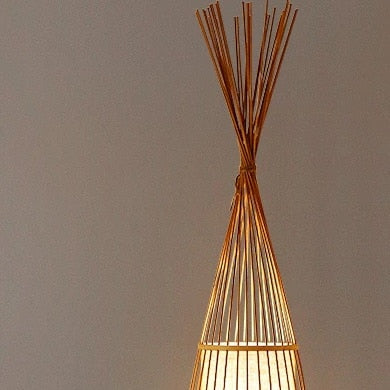 Handmade triangular rattan floor lamp with a tight weave – shown lit in a room setting (2)