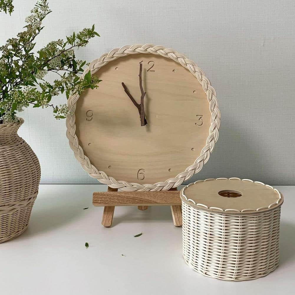 Round braided rattan wall clock with branch-shaped hands – shown in a room setting
