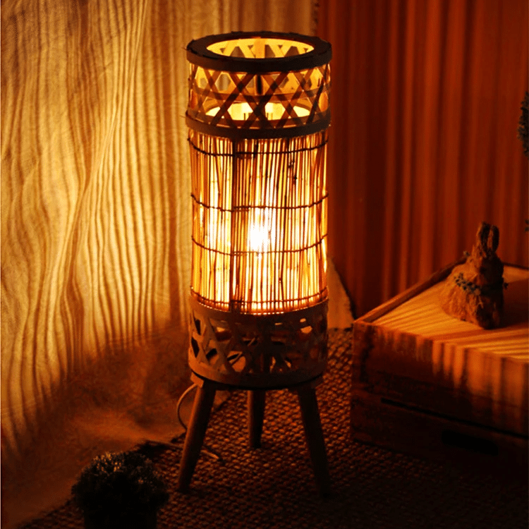 Wicker-look floor lamp with an electric candle – shown lit in a room setting (2)