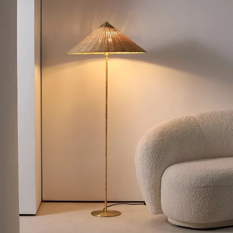 Pastoral rattan floor lamp with a large hat-shaped shade and golden base – shown in a room setting