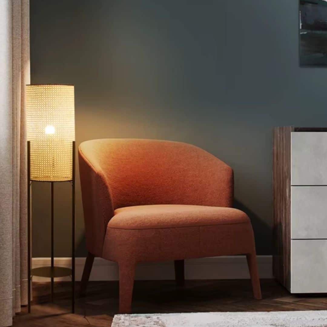 Vintage rattan tripod floor lamp with black legs – shown lit in a room setting