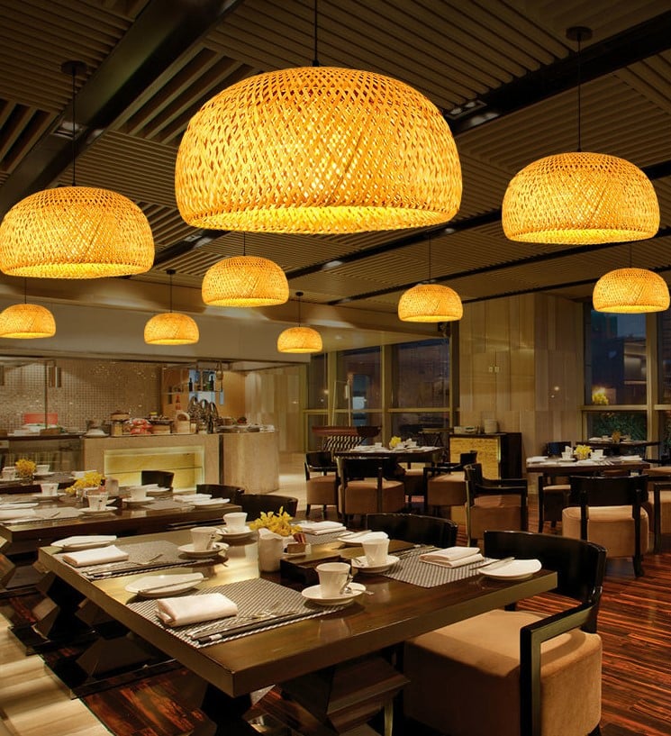 Rustic round handwoven rattan pendant light – shown lit in a room setting