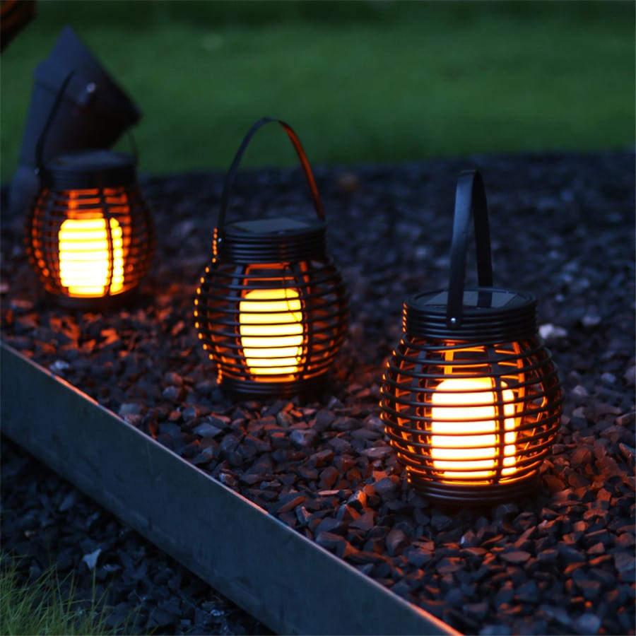 Hanging handwoven solar rattan lantern with an integrated handle – shown lit outdoors (3)
